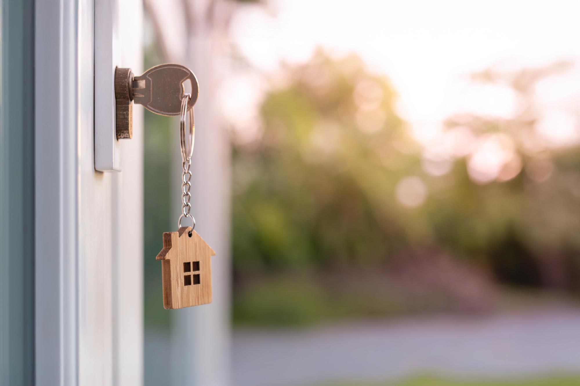 Nyckel i ett dörrlås med ett hängande hus som nyckelring